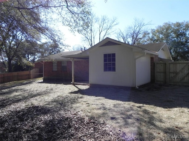 back of house featuring fence and brick siding