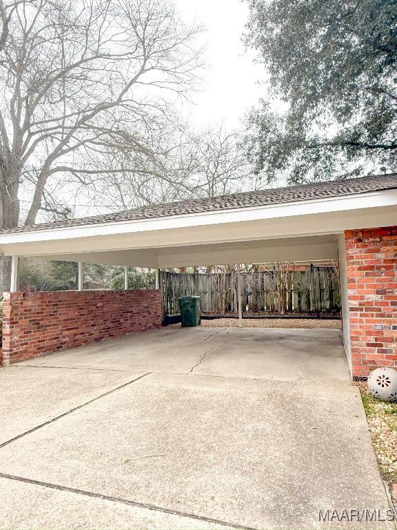 view of vehicle parking featuring a carport, driveway, and fence