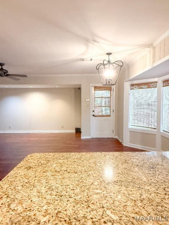 spare room featuring ceiling fan with notable chandelier, ornamental molding, wood finished floors, and baseboards