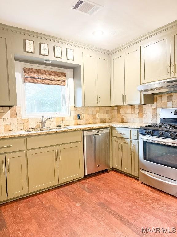 kitchen with under cabinet range hood, tasteful backsplash, visible vents, and stainless steel appliances