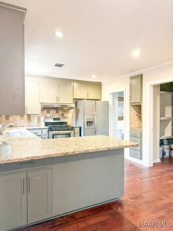 kitchen featuring gray cabinetry, under cabinet range hood, a sink, refrigerator with ice dispenser, and stainless steel gas stove