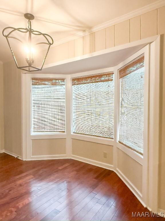 unfurnished room with wood-type flooring, ornamental molding, and a notable chandelier