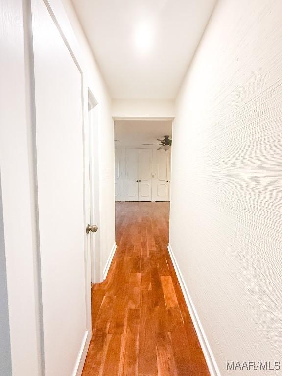 corridor with baseboards and wood finished floors