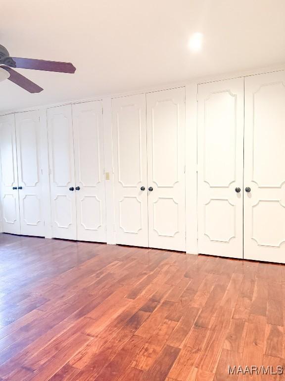 unfurnished bedroom featuring light wood-style floors, a ceiling fan, and multiple closets