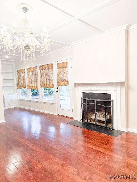 unfurnished living room with baseboards, coffered ceiling, a fireplace with flush hearth, wood finished floors, and built in shelves