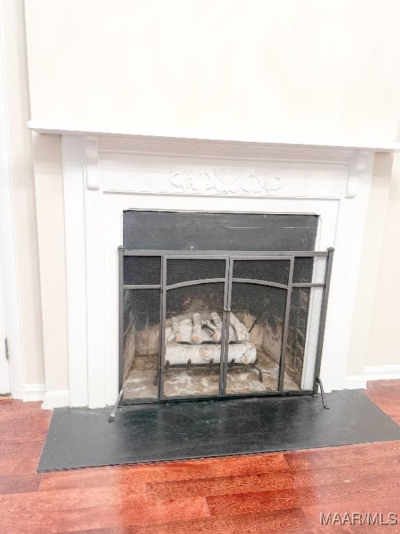 room details with a fireplace, baseboards, and wood finished floors