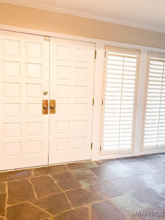 entrance foyer with stone finish floor and ornamental molding