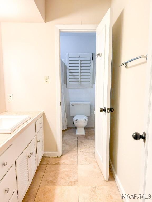 bathroom featuring toilet, vanity, baseboards, and tile patterned floors