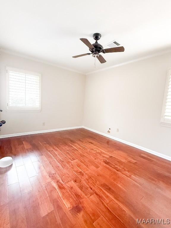 empty room featuring light wood-style floors, baseboards, visible vents, and crown molding