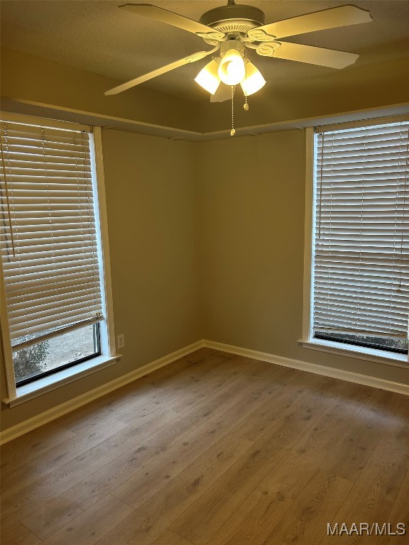 unfurnished room featuring a ceiling fan, baseboards, and wood finished floors