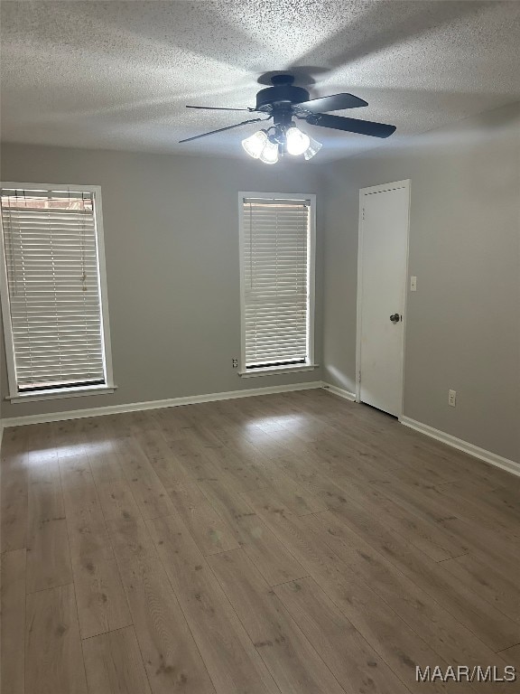 spare room featuring a ceiling fan, a textured ceiling, baseboards, and wood finished floors