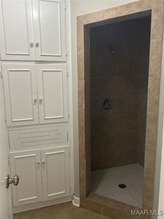 full bathroom with tile patterned flooring and a tile shower