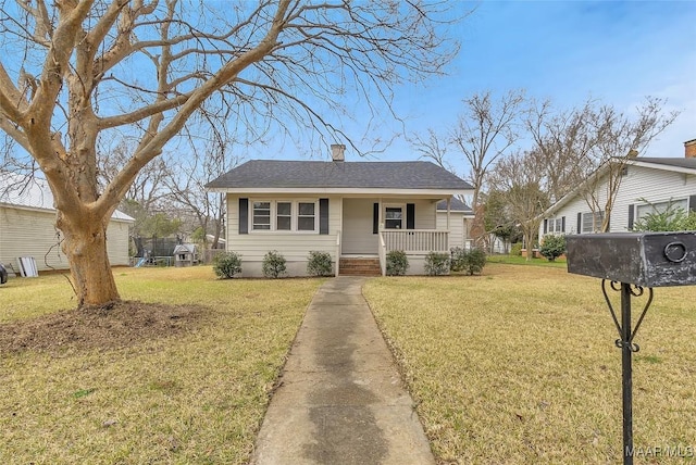 bungalow-style house featuring a porch, a chimney, a front yard, and a shingled roof