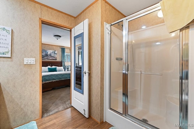 ensuite bathroom with a shower with shower door, ensuite bath, crown molding, and wood finished floors