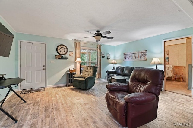 living room featuring a textured ceiling, ceiling fan, light wood finished floors, and baseboards