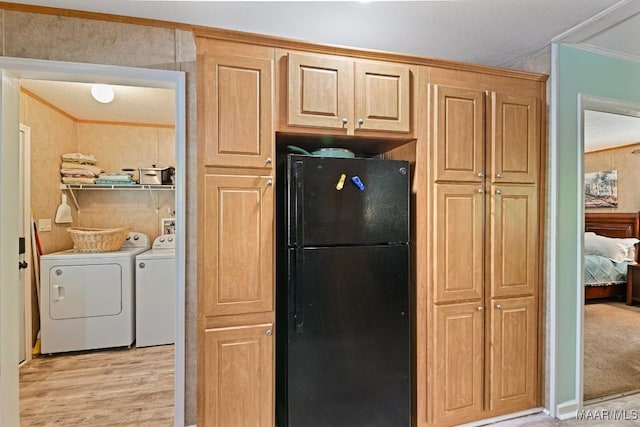 kitchen with ornamental molding, washing machine and dryer, freestanding refrigerator, and light wood-style floors