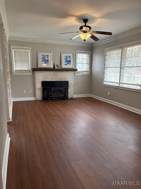 unfurnished living room with dark wood finished floors, ornamental molding, a ceiling fan, a brick fireplace, and baseboards