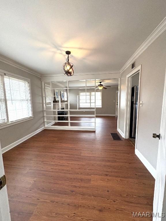 unfurnished living room with ornamental molding, dark wood finished floors, visible vents, and baseboards