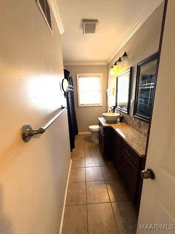 bathroom featuring tile patterned flooring, vanity, visible vents, and crown molding