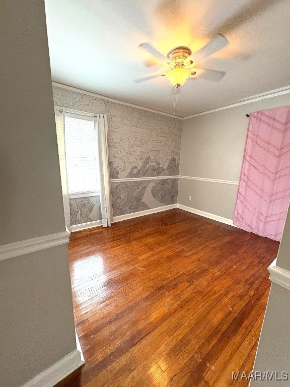 unfurnished room featuring crown molding, ceiling fan, wood finished floors, and baseboards