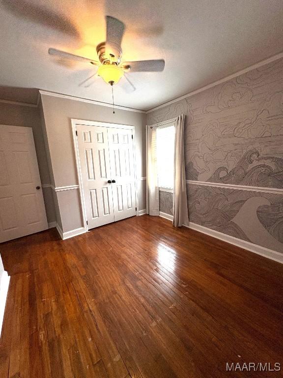 unfurnished bedroom featuring a ceiling fan, dark wood finished floors, crown molding, and baseboards