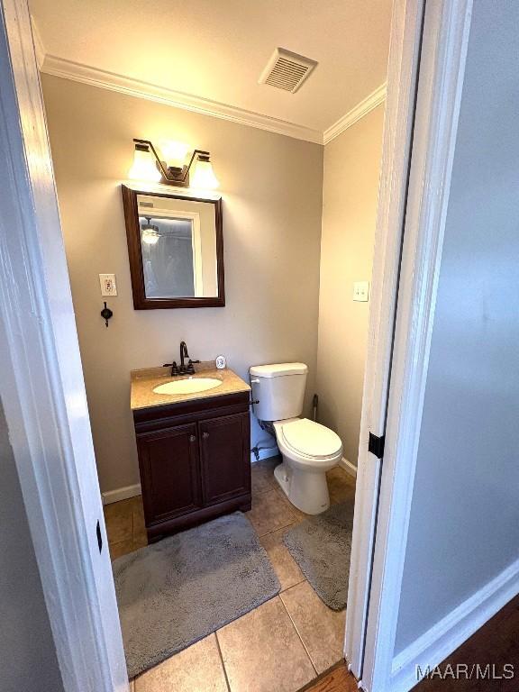 bathroom with crown molding, visible vents, toilet, vanity, and tile patterned floors