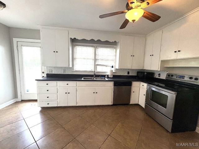 kitchen with appliances with stainless steel finishes, dark countertops, a sink, and white cabinetry