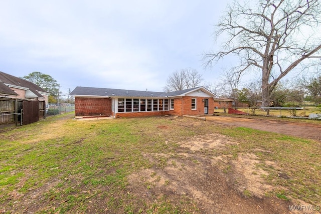 rear view of property with fence, a lawn, and brick siding