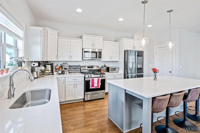 kitchen with stainless steel appliances, white cabinets, light countertops, and a sink