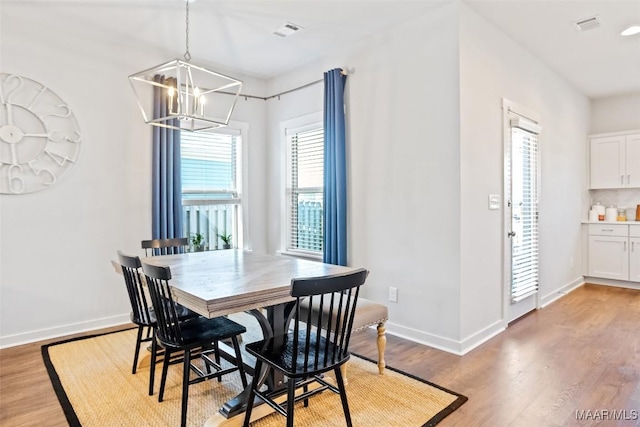 dining room with light wood-style flooring, visible vents, baseboards, and a chandelier