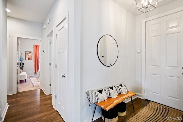 foyer entrance with a notable chandelier, dark wood-style flooring, and baseboards