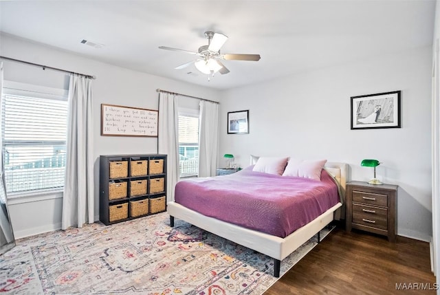 bedroom with visible vents, baseboards, ceiling fan, and dark wood-type flooring