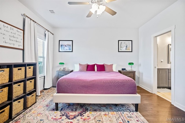 bedroom with baseboards, visible vents, a ceiling fan, wood finished floors, and ensuite bathroom