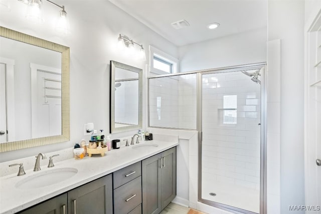 bathroom featuring double vanity, a stall shower, a sink, and visible vents