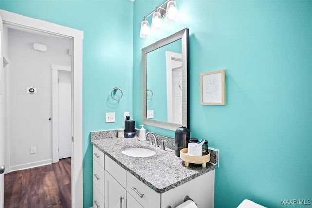 bathroom featuring baseboards, wood finished floors, and vanity