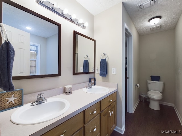 full bathroom featuring toilet, a textured ceiling, visible vents, and a sink