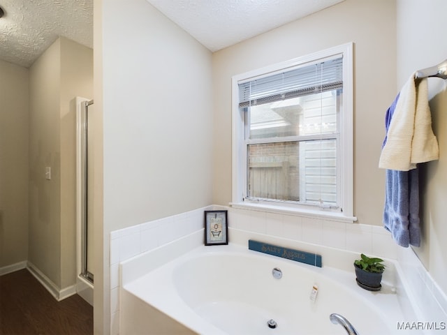 full bathroom featuring a garden tub, a shower stall, and a textured ceiling