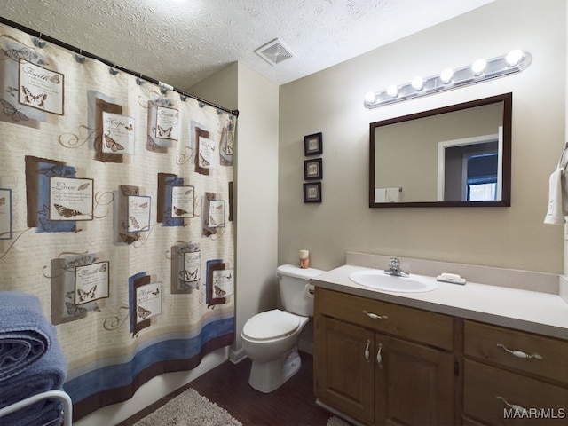 bathroom featuring visible vents, toilet, wood finished floors, a textured ceiling, and vanity