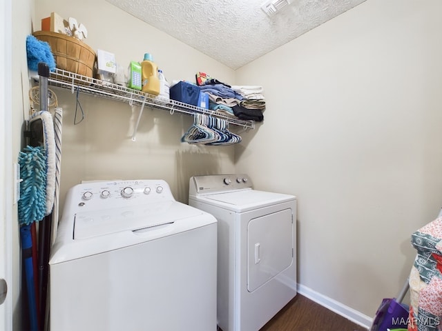 laundry area featuring dark wood-style floors, washer and clothes dryer, a textured ceiling, laundry area, and baseboards