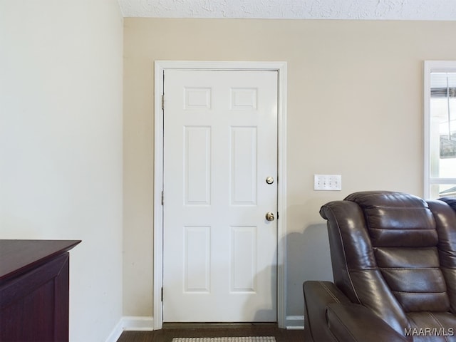 doorway to outside with a textured ceiling and baseboards