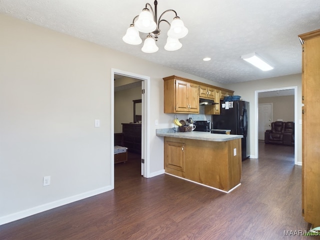 kitchen featuring dark wood-type flooring, light countertops, a peninsula, and decorative light fixtures