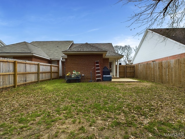 rear view of house with a patio, brick siding, a lawn, and a fenced backyard