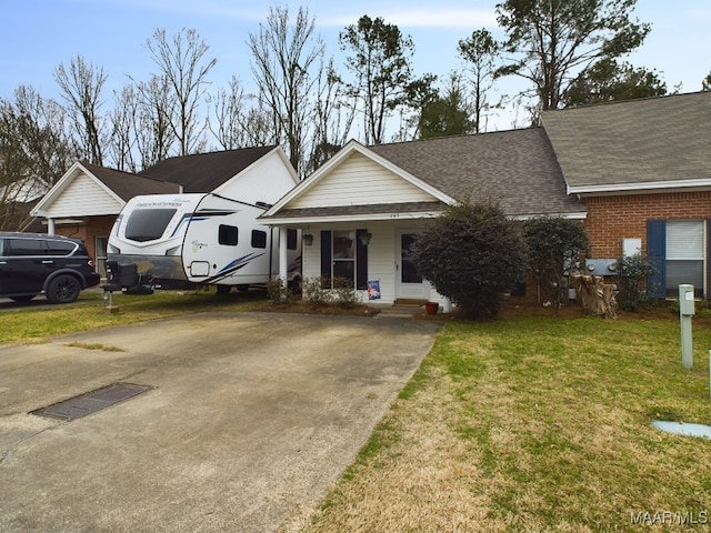 view of front of home featuring brick siding, a shingled roof, concrete driveway, covered porch, and a front yard