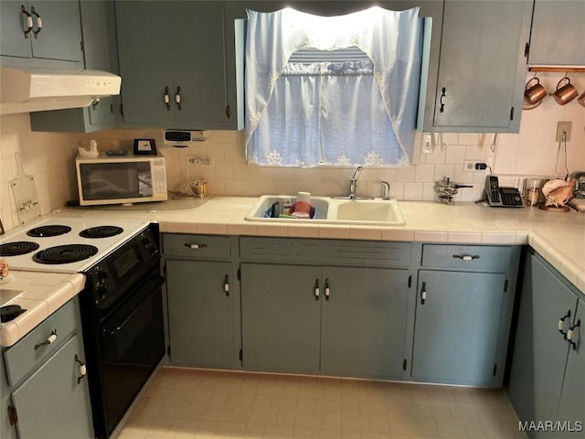 kitchen featuring black electric range, under cabinet range hood, decorative backsplash, and a sink