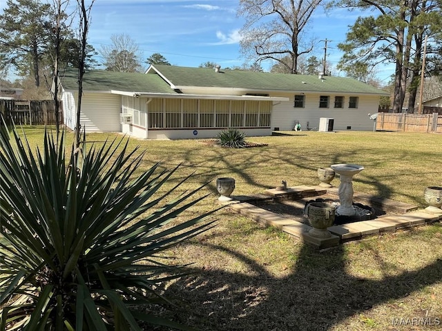 rear view of house featuring a sunroom, fence, and a lawn
