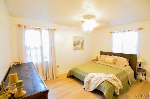 bedroom with multiple windows, light wood-type flooring, visible vents, and baseboards