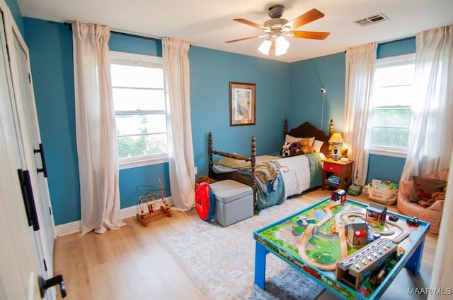 bedroom with a ceiling fan, baseboards, visible vents, and light wood finished floors