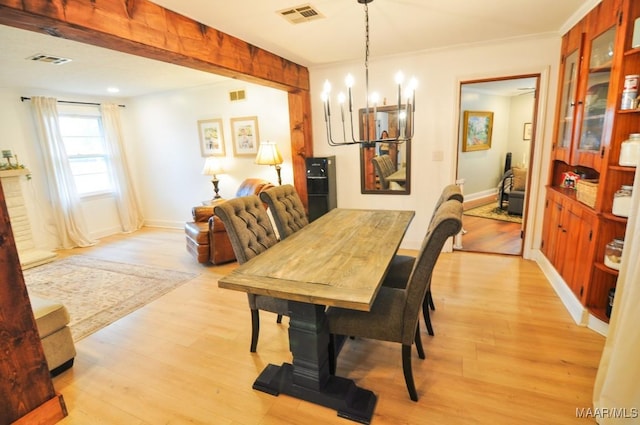 dining space featuring light wood finished floors, visible vents, and a notable chandelier