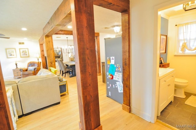 corridor featuring crown molding, decorative columns, recessed lighting, light wood-style flooring, and baseboards