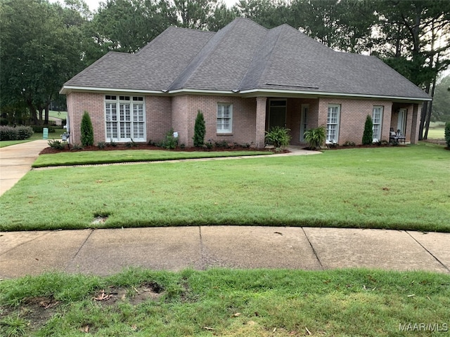 view of front of home featuring brick siding, roof with shingles, and a front yard